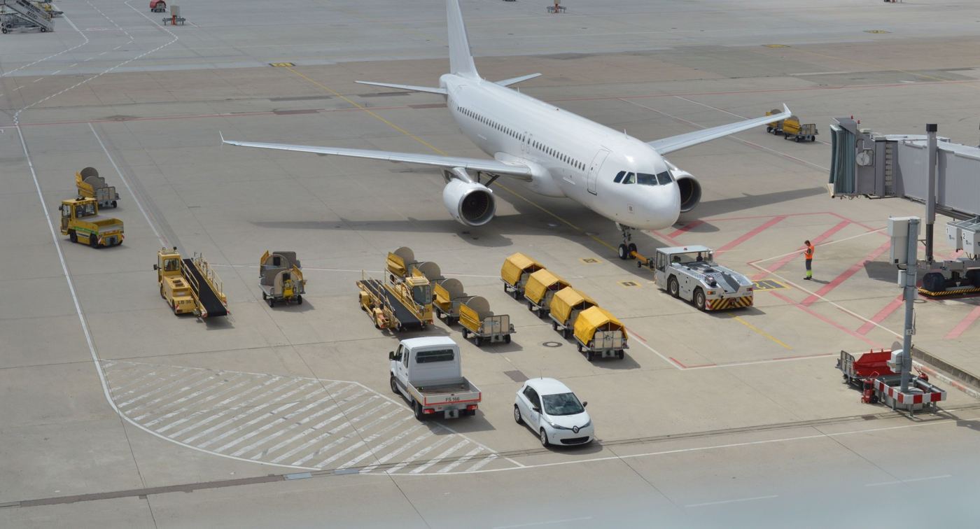 An aircraft on stand with belt loaders, baggage carts and a tug around it