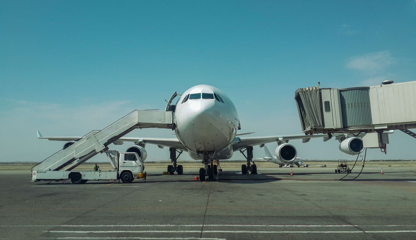 A widebody aircraft on stand with stairs and ground equipment